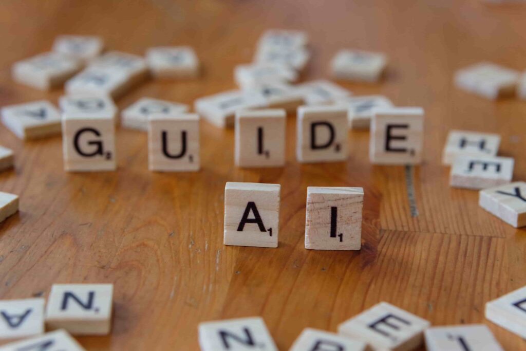 Wooden letter tiles spelling out the words "GUIDE" and "AI" on a wooden table, surrounded by extra scattered letter tiles.